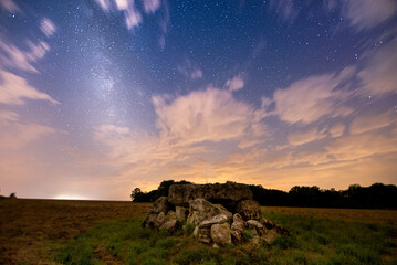 Small dolmen in a field under a starry sky with the Milky Way slightly visible
