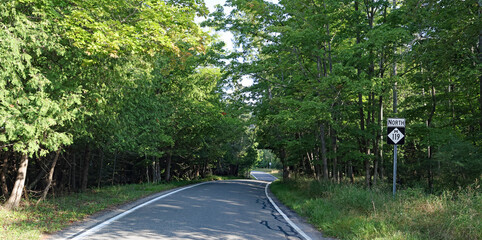 Canopied lakeshore driving route through nature parks & rustic towns, famed for vivid fall colors, in Northern Michigan near Harbor Springs.