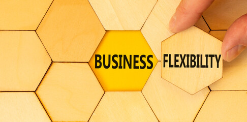 Business flexibility symbol. Concept words Business flexibility on beautiful wooden puzzles. Beautiful yellow background. Businessman hand. Business flexibility concept. Copy space.