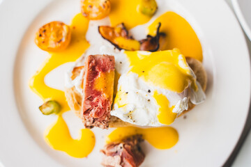 Toast with tuna, poached egg, asparagus, tomato, and hollandaise sauce close-up on a white background. Selected focus. High quality photo