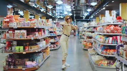 In a vibrant and colorful grocery store aisle, a trendy shopper is joyfully enjoying her time, surrounded by a lively atmosphere filled with engaging displays and cheerful products