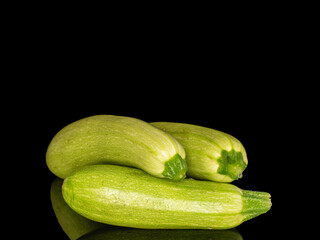 Three ripe zucchini, macro, isolated on black background.