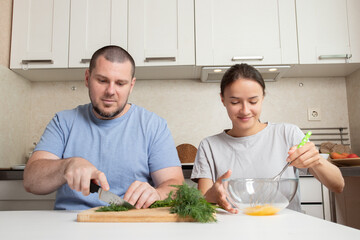 Teenager daughter and father cooking in the kitchen, beating eggs for an omelette, creating a joyful atmosphere.