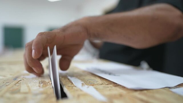 A person inserts a ballot in a box while voting at a polling station during elections.