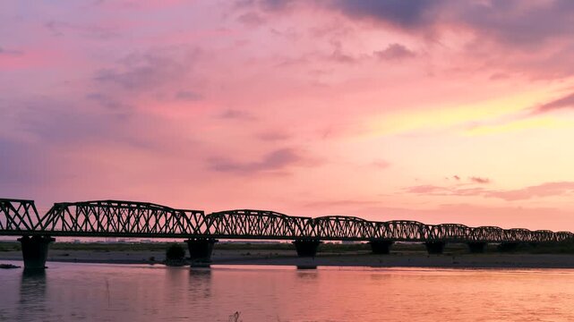 夕暮れ時の鉄道の橋を渡る列車
