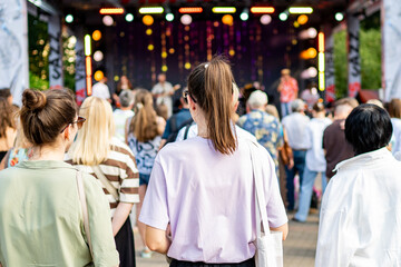 A vibrant outdoor concert with a large crowd enjoying live music under colorful stage lights....