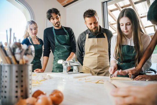 Cooking class, culinary experience of preparing ravioli, a typical Italian dish - Group of students attend the course practicing under the supervision of the chef