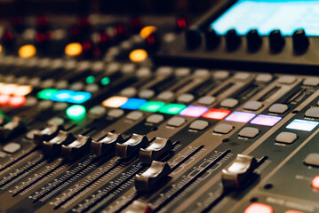Control panel with colorful lights during a live sound mixing session. A detailed view of a sound...
