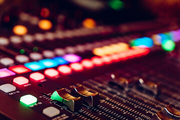 Close-up of a sound mixing console with colorful buttons and knobs. A detailed view of a sound...