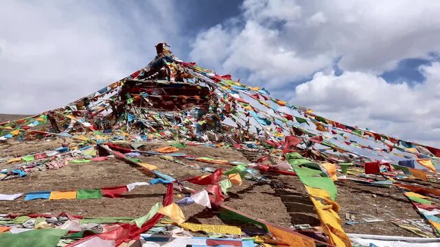 Multiple Tibetan religious prayer flags being blown with strong wind on hill next to Litang Monastery. Popular tourist landmark in Litang, Sichuan, China