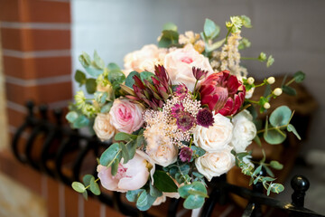 Beautiful floral bouquet with roses and greenery on a mantel. A vibrant bouquet of roses and assorted flowers arranged elegantly on a mantel.