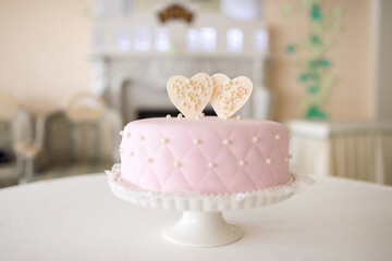 Elegant pink cake decorated with heart toppers at a special event. A beautifully decorated pink...
