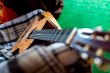 Fototapeta premium Acoustic guitar resting on a cozy blanket indoors during winter. An acoustic guitar leans against a colorful blanket in a warm indoor setting.