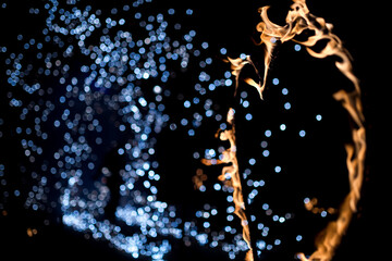 Fire dancer performing with sparks against a dark background. A performer creates swirling patterns of fire and sparks in the night.