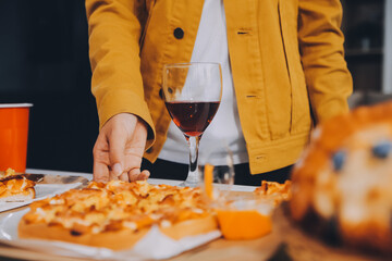 Happy friends making a toast with beer before eating pizza in a shared apartment.