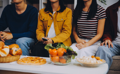 Happy friends making a toast with beer before eating pizza in a shared apartment.