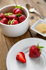 Fraise rouge sur une table en bois dans une assiette avec du sucre.