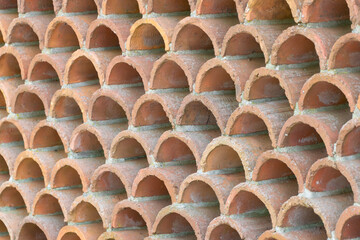 Fototapeta premium Decorative fence made of semicircular bricks, arranged in a staggered pattern, creating a unique design with gaps between the elements.