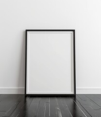Minimalistic framed picture with white background set against a modern white wall, resting on a sleek black wooden floor.