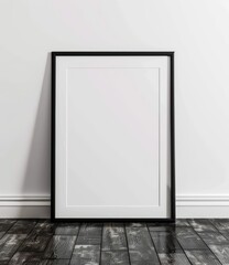 Minimalist black-framed picture on wooden floor against a clean white wall.