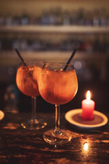 cocktail glasses on outdoor bar tabr with orange drinks and candle. cocktail glasses on outdoor bar with orange drinks at shallow depth of field