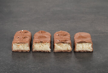 Candy bar with coconut pulp, in milk chocolate. Dark background