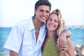 Obraz premium Smiling multiethnic woman and man enjoying vacation. Beautiful and cheerful couple of generation z pose for a photo with a mobile phone.