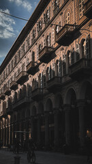 Sunlit Italian palazzo casts long shadows on cobblestone street. Arched windows and ornate...