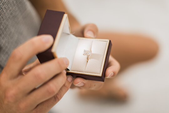 Man proposing with a beautiful emerald cut diamond ring in a box - Powered by Adobe
