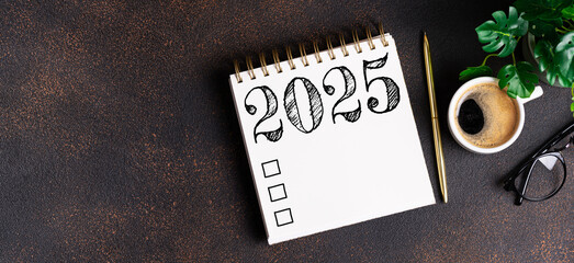 New year resolutions 2025 on desk. 2025 goals list with notebook, coffee cup, plant on table....
