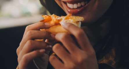 Funny brunette girl in yellow sweater eating pizza at restaurant.