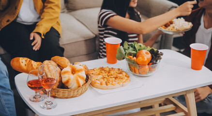 Happy friends making a toast with beer before eating pizza in a shared apartment.