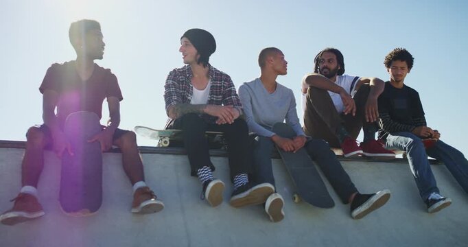 Friends, talking and men with skateboard in park for exercise, practice and hobby activity in city. Diversity, skater group and people in discussion for adventure, skateboarding and training outdoors