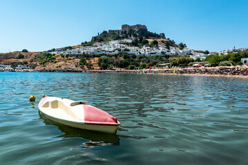View of sandy beach in Bay of Lindos, with Lindos town and  Acropolis in background (Rhodes, Greece)