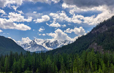 snow mountains between green ones under white clouds