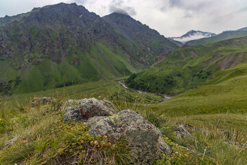Naklejka premium stones in front of Caucasus mountain under grey clouds