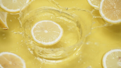 Close up of fresh lemon slices water splashing on separated yellow background. Macrography of...
