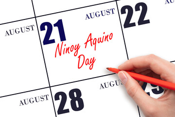 August 21. Hand writing text Ninoy Aquino Day on calendar date. Save the date.