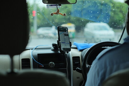Uber driver in india with smartphone inside car. Uber is an American company offering transportation services in Delhi India : August 2024