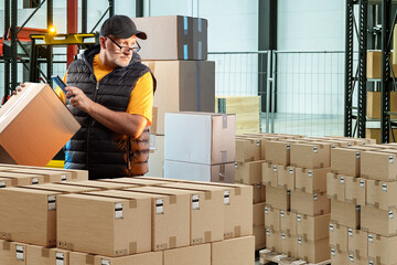 Man works in logistics postal center. Retail warehouse manager. Man with boxes inside industrial...