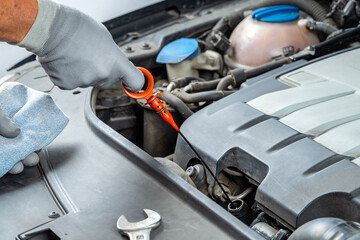 Mechanic checking lubricant oil level of a car with dipstick in the workshop. Vehicles maintenance.