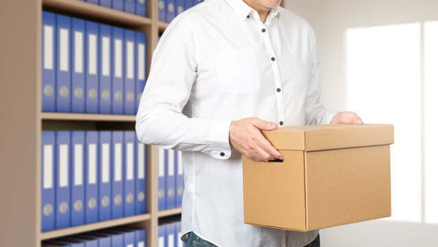 Man is standing in archive room. There stack of documents behind guy. Archivist at work. Lawyer carries box of documents. Cropped male works in archive. Storage and processing of accounting papers