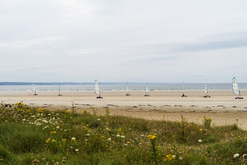 Plage de sable doré et mer d'Iroise en Bretagne, avec des chars à voile sur le sable, sous un...