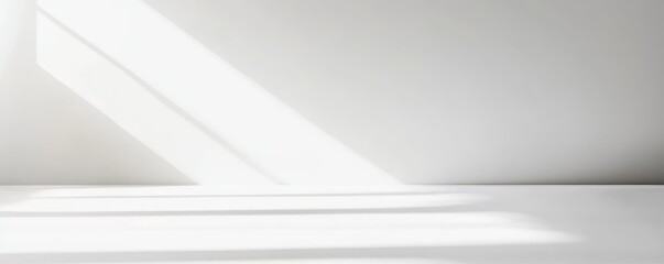 Minimalist white interior with natural light streaming through a window, casting geometric shadows on the smooth surface.