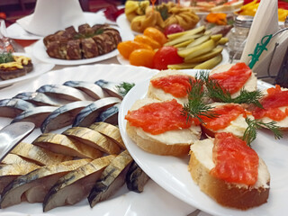 Pieces of smoked mackerel sandwiches with red fish on the table.. Set of dishes