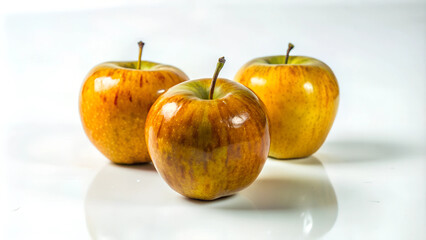 Three shiny apples on white reflective surface with copy space