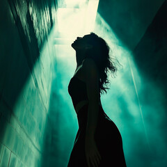 Attractive female model posing in profile, against a dark and bright backlit backdrop.