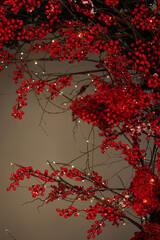 A tree with red berries is lit up with lights