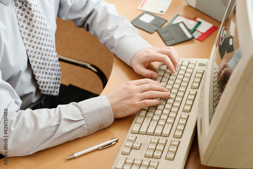 Aufkleber Person in formal attire typing on computer keyboard in office setting with various office supplies scattered on desk creating professional environment