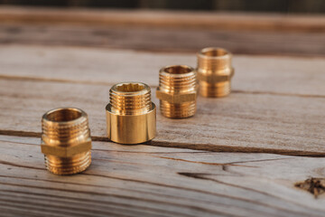 Brass plumbing fittings lying on a rustic wooden table on a sunny day (selective focus)